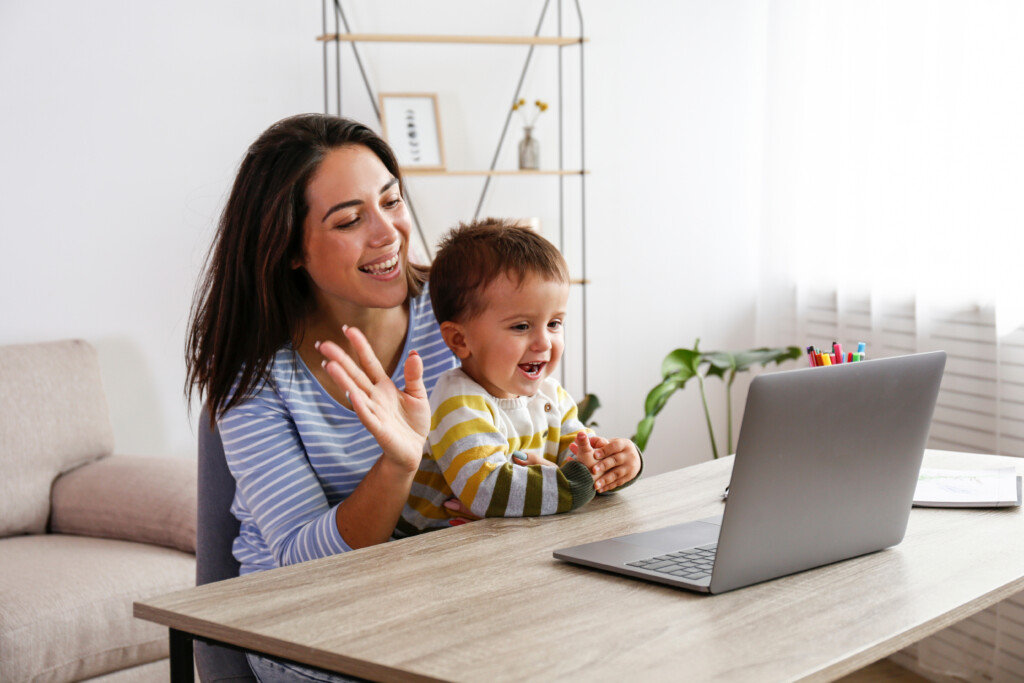 jeune mère avec enfant souriant dans leur salon en regardant un portable qui apprendent une langue