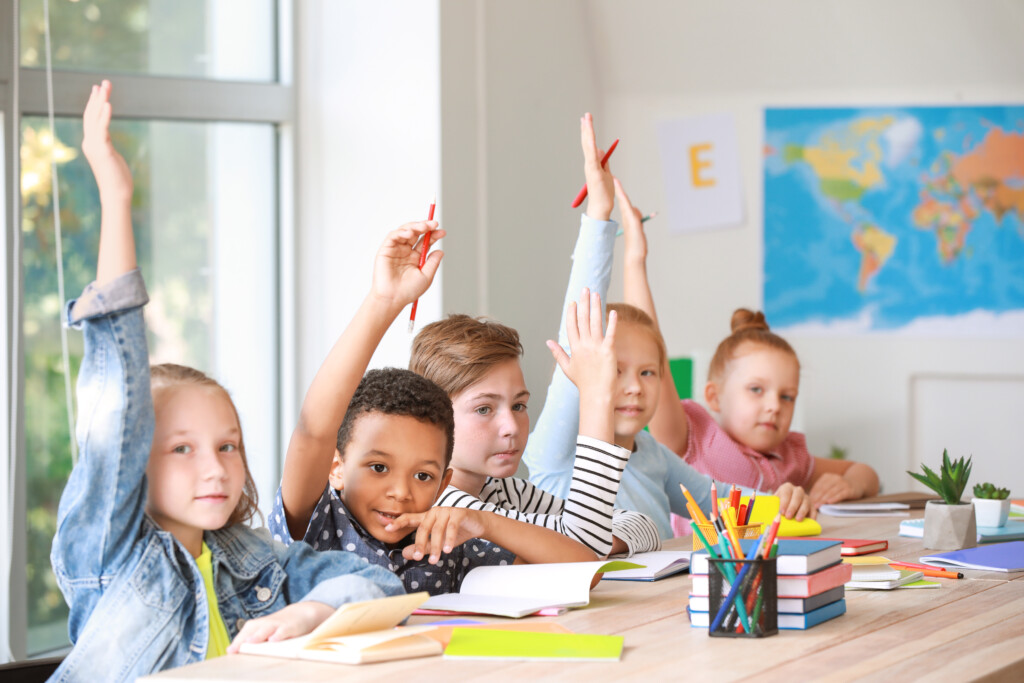 Children in a classroom raising their handstogether