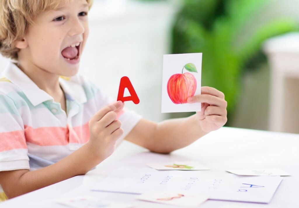 enfant jouant a un jeux de cartes avec la lettre a et une pomme.