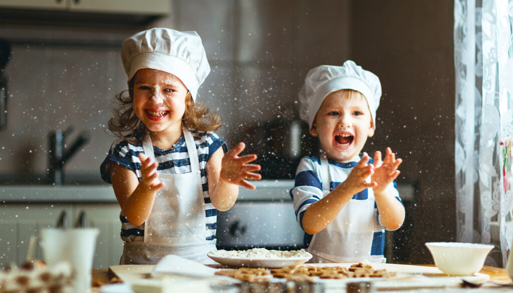 enfants contents jouant et souriant dans une cuisine jouant au chefs cuisiniers