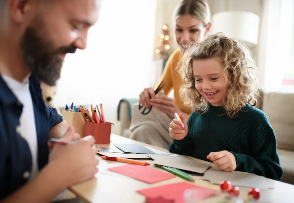 A happy family sitting together at a table, smiling while drawing and making crafts with colorful paper and pencils in a cozy living room. Une famille souriante réunie autour d'une table, s'amusant à dessiner et à bricoler avec du papier coloré et des crayons dans un salon chaleureux. erreurs