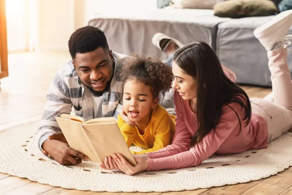 Parents and child reading a bilingual book together at home Parent et enfant lisant ensemble un livre bilingue pour favoriser l'apprentissage d'une langue seconde à la maison.