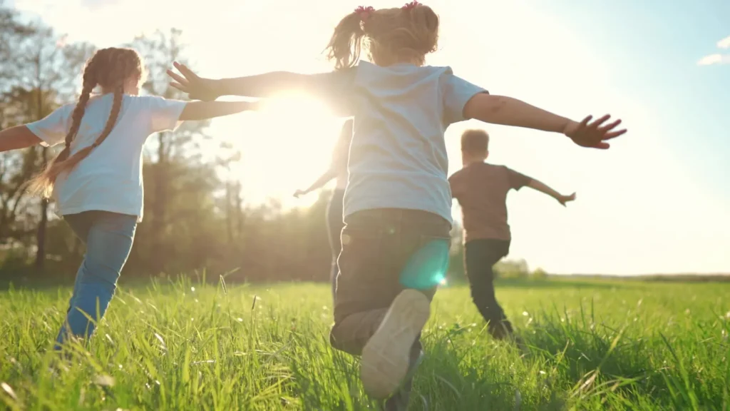 Group of children playing outdoors in a nature-based summer camp setting. Enfants qui jouent dehors dans un camp d'été axé sur la nature. plein air outdoors